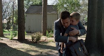 Movie still from “The Tree of Life” (2011), directed by Terrence Malick – A man in a suit holding a little boy in his arms; Medium shot, Over the shoulder angle