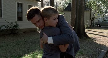 Movie still from “The Tree of Life” (2011), directed by Terrence Malick – A man and a young boy hugging each other in a yard; Medium shot, Low angle