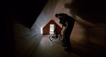 Movie still from “The Tree of Life” (2011), directed by Terrence Malick – A man and a child riding a bike inside a house; Extreme Wide shot, Low angle