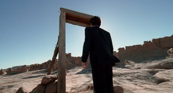 Movie still from “The Tree of Life” (2011), directed by Terrence Malick – A man in a black suit standing in front of an arch; Wide shot, Low angle