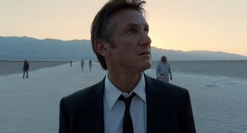Movie still from “The Tree of Life” (2011), directed by Terrence Malick – A man in a suit and tie standing on the beach; Close Up shot, Over the shoulder angle