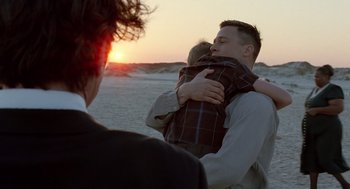 Movie still from “The Tree of Life” (2011), directed by Terrence Malick – A man holding a child in his arms at the beach; Medium shot, Over the shoulder angle