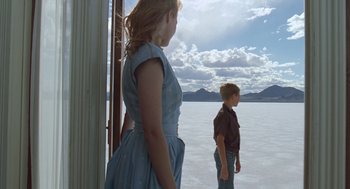 Movie still from “The Tree of Life” (2011), directed by Terrence Malick – A woman standing next to a young boy in front of a lake; Wide shot, Low angle