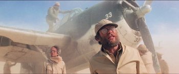 Movie still from “Close Encounters of the Third Kind” (1977), directed by Steven Spielberg – A man with a hat and glasses standing in front of an airplane; Medium shot, Low angle