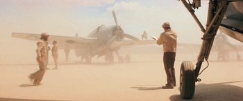 Movie still from “Close Encounters of the Third Kind” (1977), directed by Steven Spielberg – A man standing in front of an airplane in the desert; Wide shot, Low angle