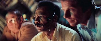 Movie still from “Close Encounters of the Third Kind” (1977), directed by Steven Spielberg – A man with a headset on and another man standing next to him; Close Up shot, Low angle