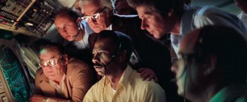 Movie still from “Close Encounters of the Third Kind” (1977), directed by Steven Spielberg – A group of people standing around a man with a headset; Close Up shot, Low angle