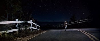 Movie still from “Close Encounters of the Third Kind” (1977), directed by Steven Spielberg – A person is running on the street at night; Extreme Wide shot, Low angle