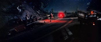 Movie still from “Close Encounters of the Third Kind” (1977), directed by Steven Spielberg – A person standing on the side of a road at night; Extreme Wide shot, High angle