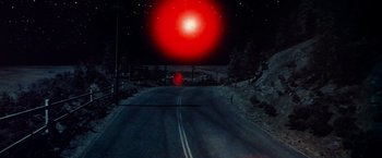 Movie still from “Close Encounters of the Third Kind” (1977), directed by Steven Spielberg – A road with a red light on the side of the road; Extreme Wide shot, High angle