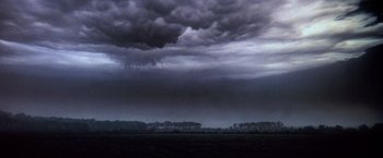 Movie still from “Close Encounters of the Third Kind” (1977), directed by Steven Spielberg – A dark cloudy sky over a field with trees; Extreme Wide shot, Low angle