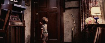 Movie still from “Close Encounters of the Third Kind” (1977), directed by Steven Spielberg – A little boy that is standing in front of a door; Medium shot, Over the shoulder angle