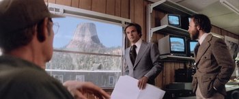 Movie still from “Close Encounters of the Third Kind” (1977), directed by Steven Spielberg – A man wearing a suit and tie holding papers; Medium shot, Low angle