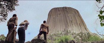 Movie still from “Close Encounters of the Third Kind” (1977), directed by Steven Spielberg – A man standing on top of a rock looking up at a rock formation; Extreme Wide shot, Low angle
