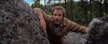 Movie still from “Close Encounters of the Third Kind” (1977), directed by Steven Spielberg – A man climbing a rock in the woods; Close Up shot, Low angle