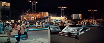 Movie still from “Close Encounters of the Third Kind” (1977), directed by Steven Spielberg – A group of people sitting in a room at night; Extreme Wide shot, High angle