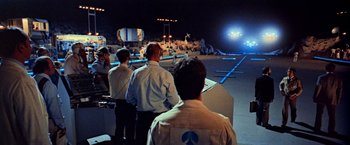 Movie still from “Close Encounters of the Third Kind” (1977), directed by Steven Spielberg – A group of men standing next to each other in a room; Extreme Wide shot, High angle