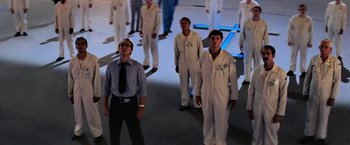 Movie still from “Close Encounters of the Third Kind” (1977), directed by Steven Spielberg – A group of men in white suits standing in a room; Wide shot, High angle