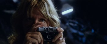 Movie still from “Close Encounters of the Third Kind” (1977), directed by Steven Spielberg – A woman taking a picture with a camera; Close Up shot, Low angle