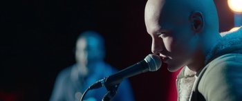 Movie still from “Clouds” (2020), directed by Justin Baldoni – A man with a bald head is singing into a microphone; Close Up shot, Low angle