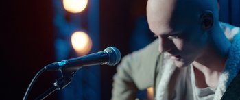 Movie still from “Clouds” (2020), directed by Justin Baldoni – A bald man with a bald head is holding a microphone; Extreme Close Up shot, Low angle