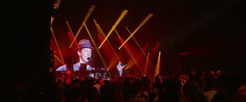 Movie still from “Clouds” (2020), directed by Justin Baldoni – A man singing on a stage with a microphone; Wide shot, High angle