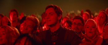 Movie still from “Clouds” (2020), directed by Justin Baldoni – A young man is standing in a crowd of people; Close Up shot, Over the shoulder angle