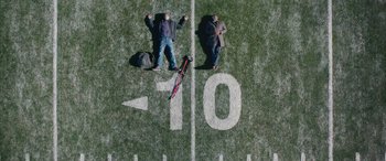 Movie still from “Clouds” (2020), directed by Justin Baldoni – Two men are standing on a football field; Extreme Wide shot, Overhead angle