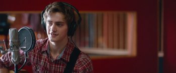 Movie still from “Clouds” (2020), directed by Justin Baldoni – A young man wearing headphones while standing in a room; Close Up shot, Over the shoulder angle