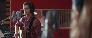 Movie still from “Clouds” (2020), directed by Justin Baldoni – A young man wearing headphones while standing in a room; Close Up shot, Over the shoulder angle