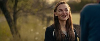 Movie still from “Clouds” (2020), directed by Justin Baldoni – A young woman smiles brightly while standing in a field; Close Up shot, Over the shoulder angle