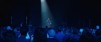 Movie still from “Clouds” (2020), directed by Justin Baldoni – A man in a gray suit standing in front of an audience; Extreme Wide shot, High angle