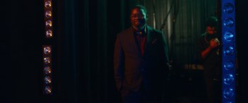 Movie still from “Clouds” (2020), directed by Justin Baldoni – A man in a suit standing in front of a curtain; Medium shot, Low angle