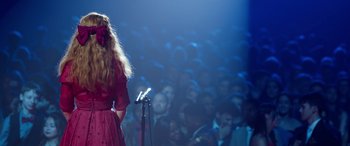 Movie still from “Clouds” (2020), directed by Justin Baldoni – A woman standing on a stage holding a microphone; Medium shot, Over the shoulder angle