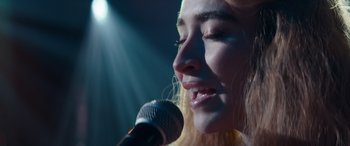 Movie still from “Clouds” (2020), directed by Justin Baldoni – A woman is singing into a microphone in the dark; Close Up shot, Low angle