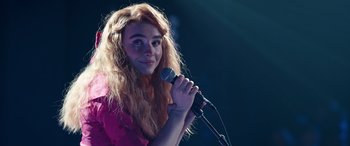 Movie still from “Clouds” (2020), directed by Justin Baldoni – A woman with long blonde hair is holding a microphone; Close Up shot, Over the shoulder angle