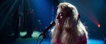 Movie still from “Clouds” (2020), directed by Justin Baldoni – A woman with long hair is singing into a microphone; Close Up shot, High angle