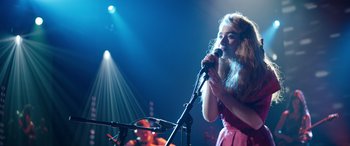 Movie still from “Clouds” (2020), directed by Justin Baldoni – A woman is singing into a microphone on stage; Medium shot, High angle