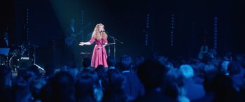 Movie still from “Clouds” (2020), directed by Justin Baldoni – A woman standing on a stage with a microphone in front of a group of people; Wide shot, Over the shoulder angle