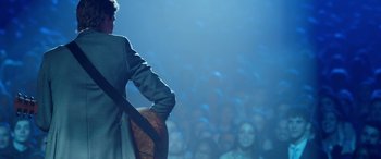 Movie still from “Clouds” (2020), directed by Justin Baldoni – A man standing in front of an audience holding a guitar; Medium shot, Over the shoulder angle