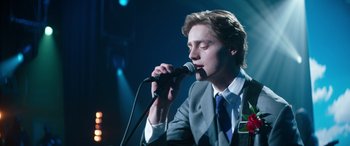 Movie still from “Clouds” (2020), directed by Justin Baldoni – A man in a suit and tie holding a microphone; Close Up shot, Low angle