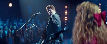 Movie still from “Clouds” (2020), directed by Justin Baldoni – A man standing in front of a microphone on a stage; Medium shot, Over the shoulder angle