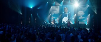 Movie still from “Clouds” (2020), directed by Justin Baldoni – A large crowd of people watching a man on a video screen; Wide shot, High angle