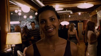 Movie still from “Cloverfield” (2008), directed by Matt Reeves – A woman smiling for the camera in front of a group of people; Close Up shot, Over the shoulder angle