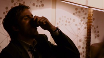 Movie still from “Cloverfield” (2008), directed by Matt Reeves – A man in a suit and tie drinking from a cup; Close Up shot, High angle