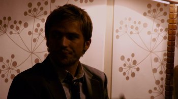 Movie still from “Cloverfield” (2008), directed by Matt Reeves – A person wearing a suit and tie; Close Up shot, Over the shoulder angle