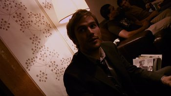 Movie still from “Cloverfield” (2008), directed by Matt Reeves – A man in a suit and tie in front of a lamp; Close Up shot, Over the shoulder angle