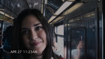 Movie still from “Cloverfield” (2008), directed by Matt Reeves – A woman is smiling on a train; Extreme Close Up shot, Over the shoulder angle