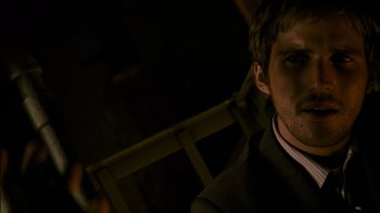 Movie still from “Cloverfield” (2008), directed by Matt Reeves – A man in a black suit and white shirt; Close Up shot, High angle