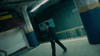 Movie still from “Cloverfield” (2008), directed by Matt Reeves – A man wearing a suit and tie in an empty parking garage; Wide shot, Low angle